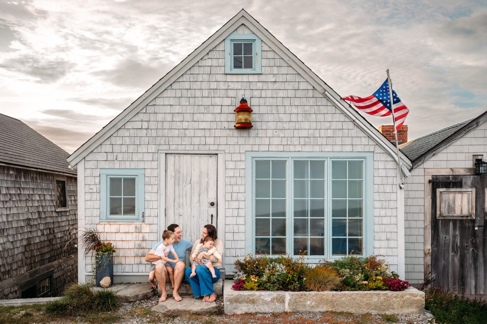 Family sitting in front of fishing cottage in North Hampton, NH at their beach mini session