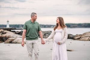 Expectant couple walking at Newcastle Commons beach during their maternity session.