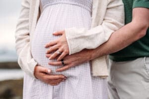 Cradling belly at Newcastle Commons maternity beach photo session