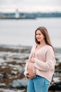 Mom to be holding belly at maternity photo session in Newcastle, NH