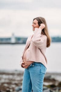 Mom to be holding belly at maternity photo session in Newcastle, NH