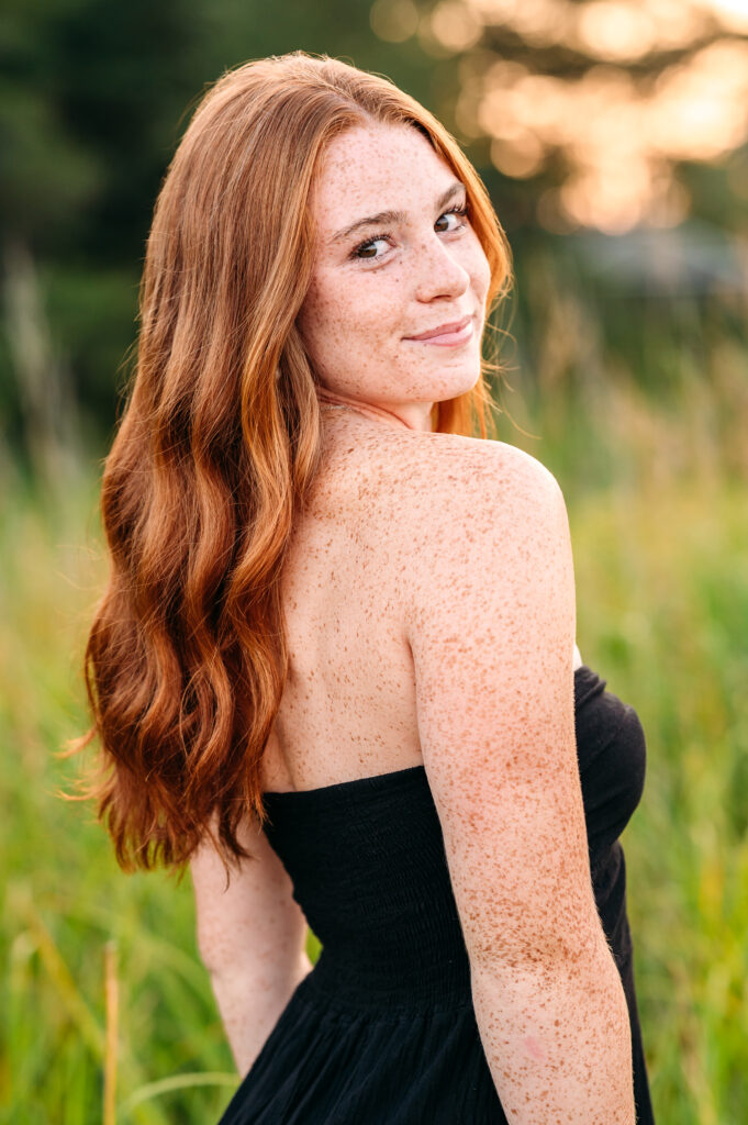 Redhead senior girl smiling at camera during NH senior photo session.
